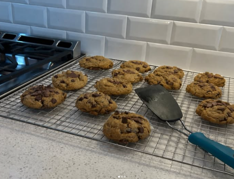 A fresh batch of chocolate chip cookies on a cooling rack beside the stove